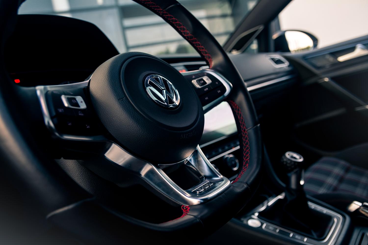 The interior of a Volkswagen showing the steering wheel, centre console and gear lever.